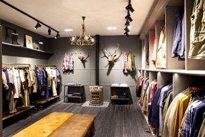 An interior of an apparel store with some apparels hanging and some decor pieces on the wall.